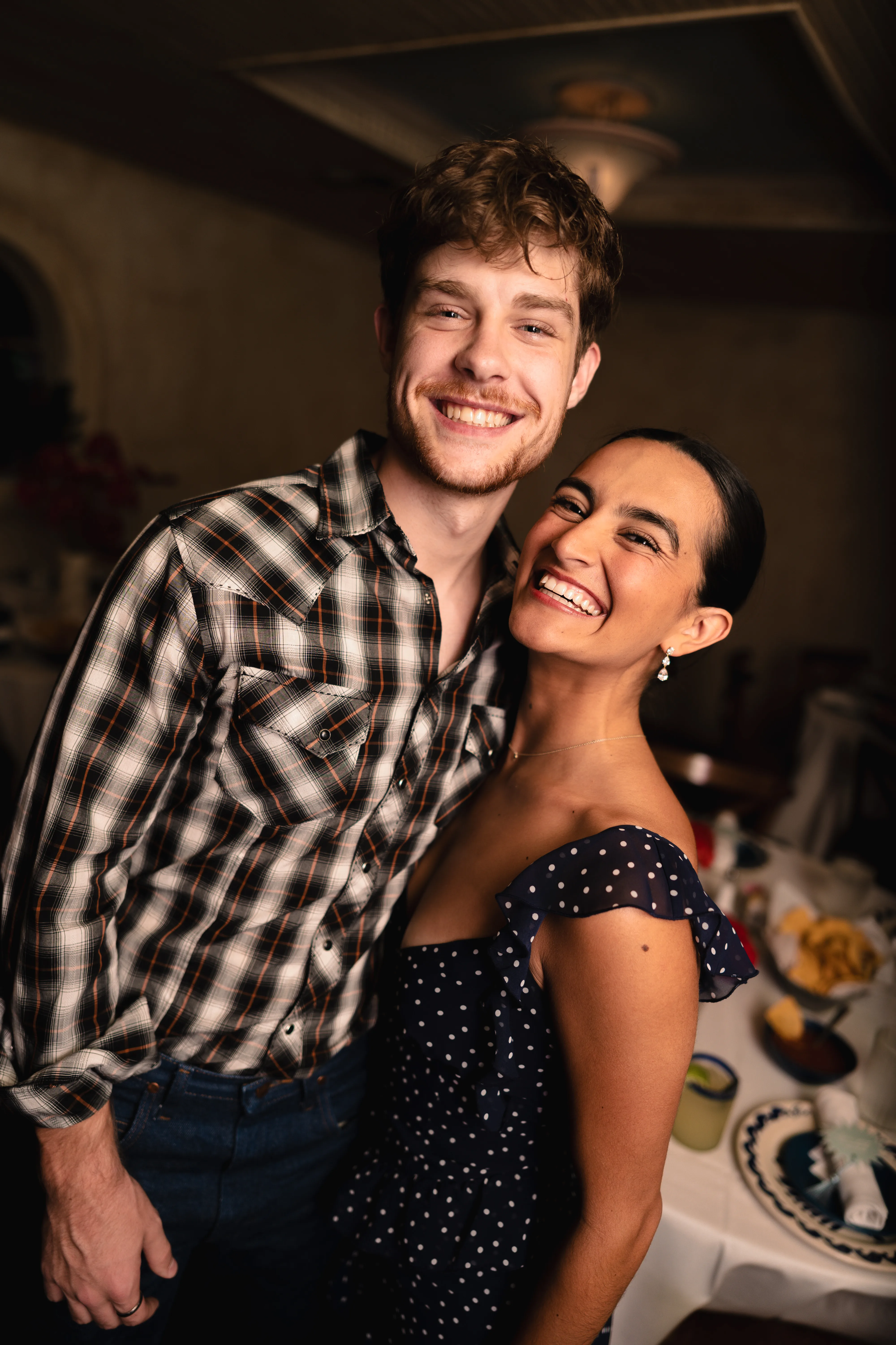 Couple laughing together at an indoor gathering, candid black and white portrait