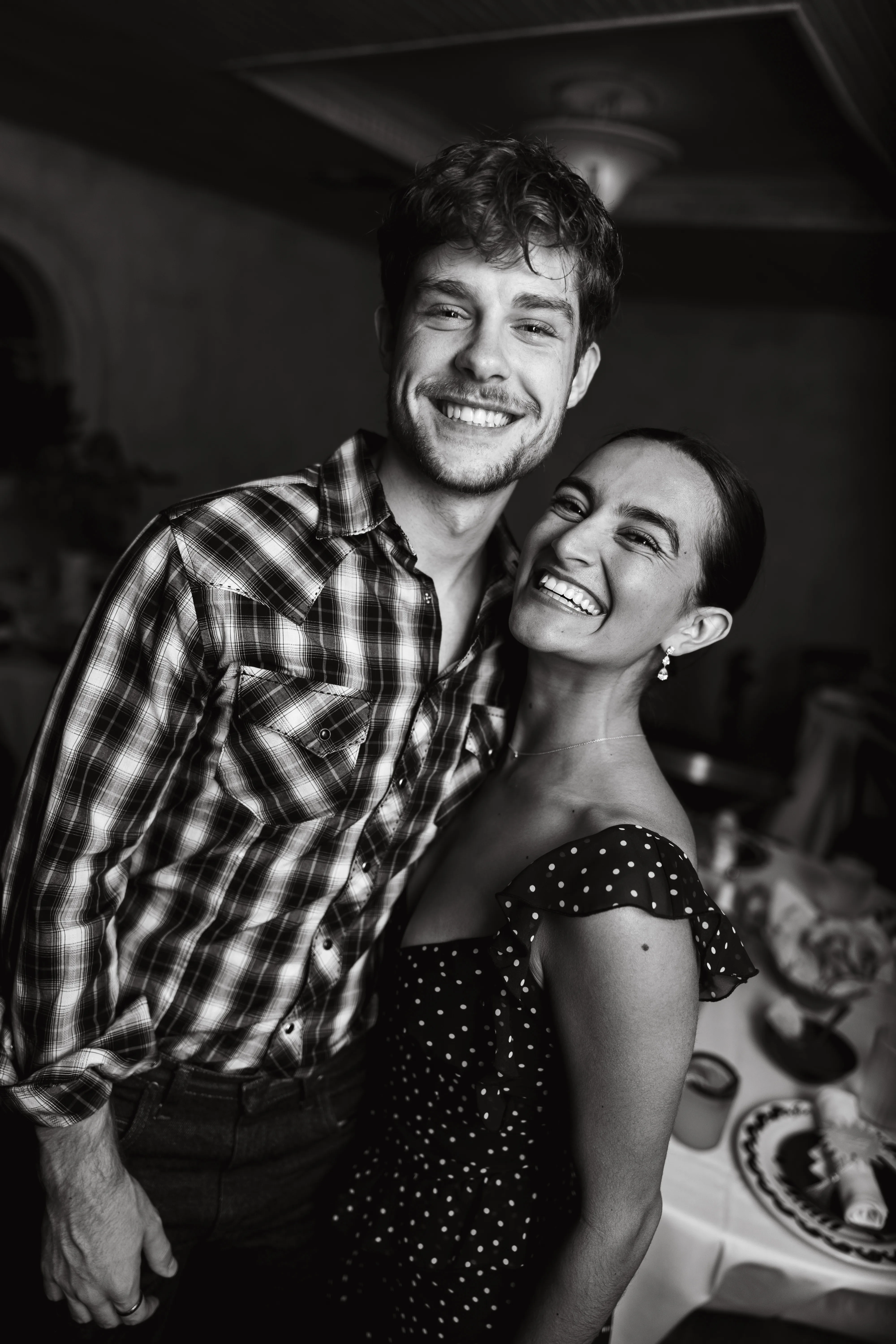 Couple laughing together at an indoor gathering, candid black and white portrait