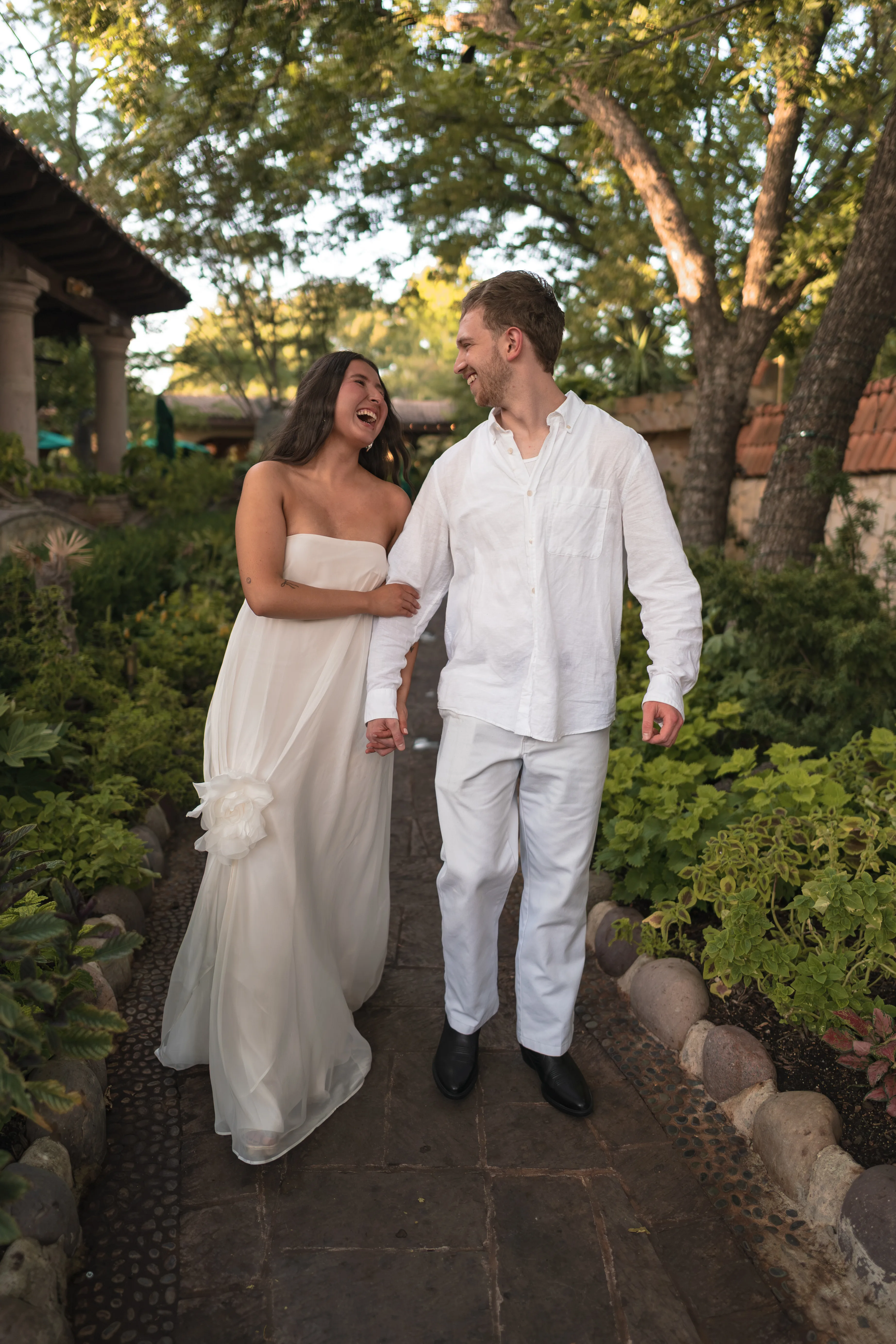 Couple walking arm in arm through a garden pathway, laughing