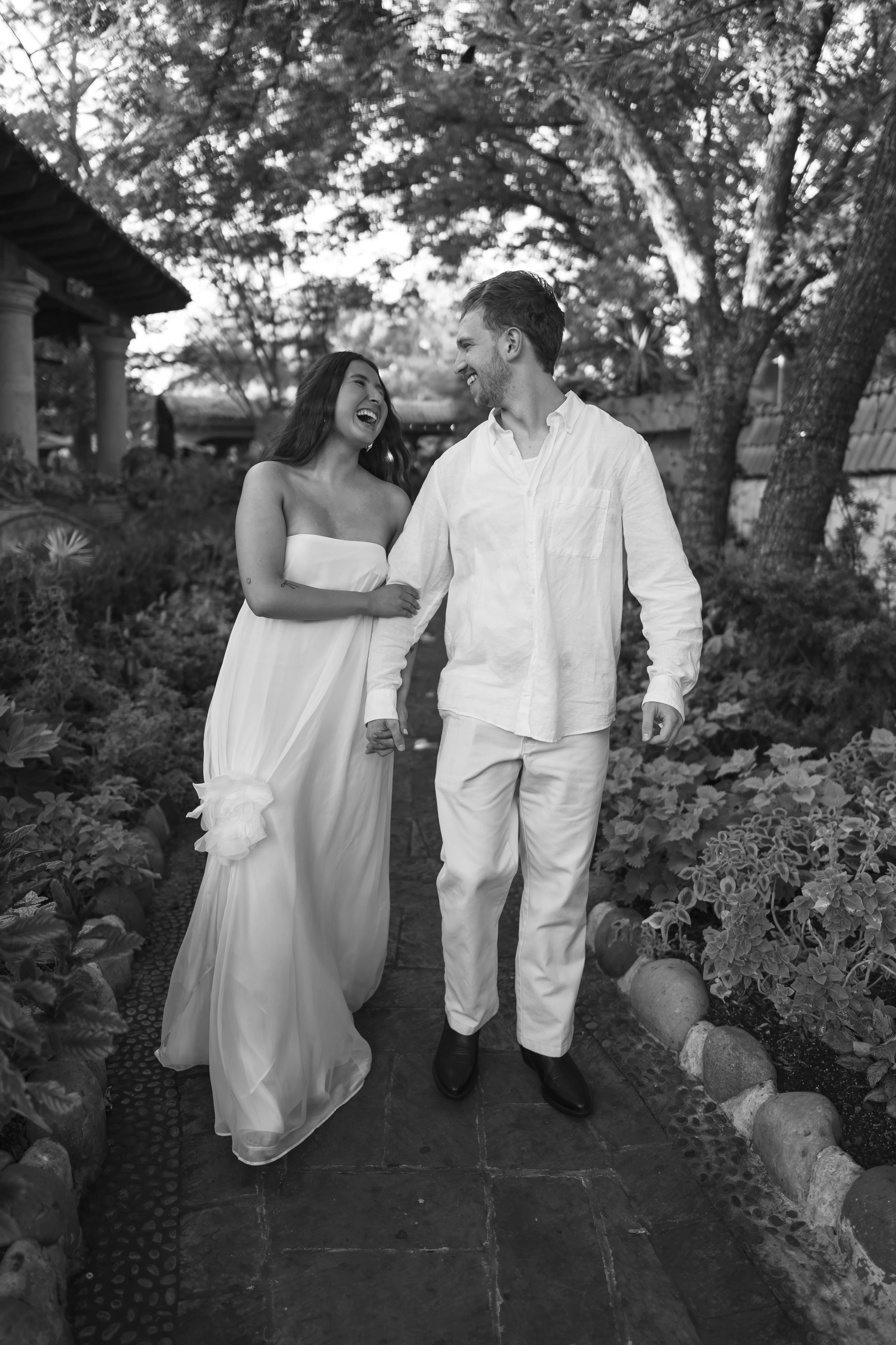 Couple walking arm in arm through a garden pathway, laughing